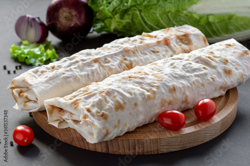 Two large Shawarma on a wooden Board with tomatoes