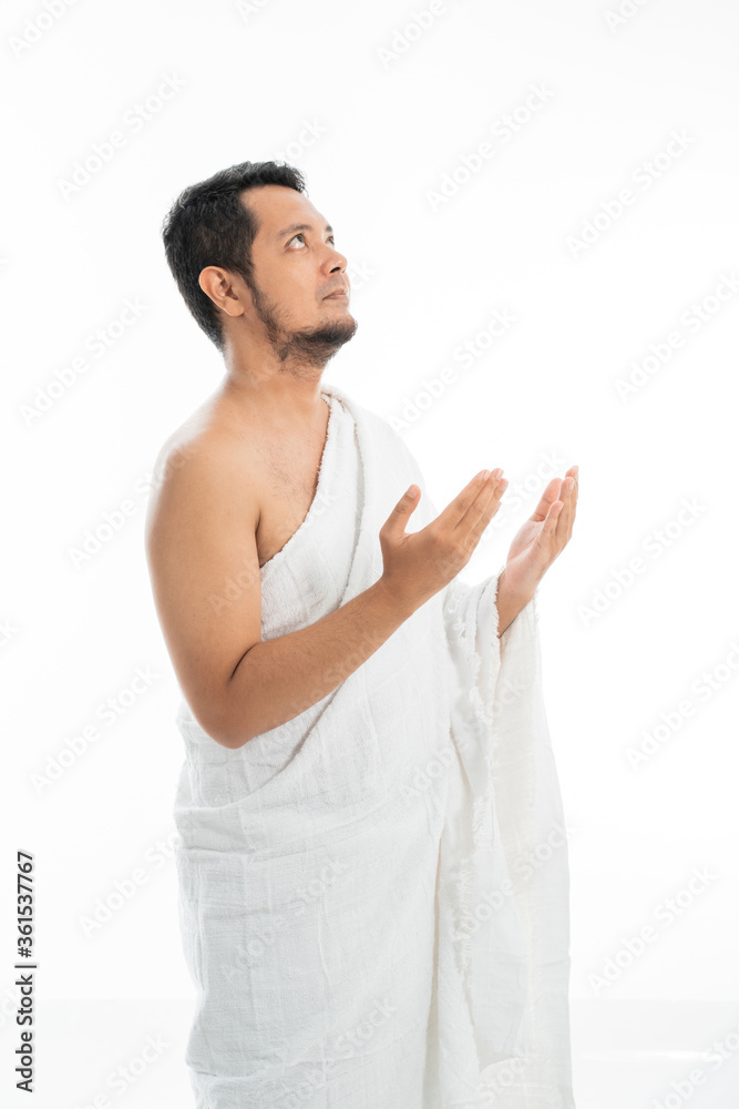Muslim man praying while standing in white traditional clothes open his arm Muslim man praying while standing in white traditional clothes open his arm