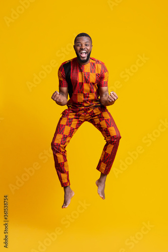 Emotional black man in red african costume celebrating success