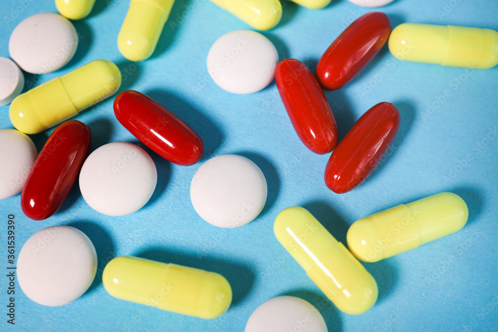 Pills, tablets and glass of water on blue background top view. Medical pharmacy concept.multi-colored pills on a blue background. view from above Pills, tablets and glass of water on blue background top view. Medical pharmacy concept.multi-colored pills on a blue background. view from above