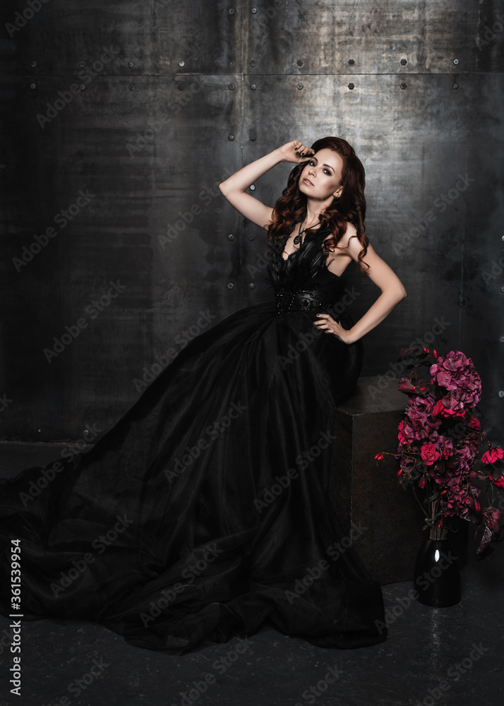 Young beautiful brunette woman standing in the palace room.Sexy girl.Halloween.Portrait of a girl in black.Beautiful woman in a darck room Young beautiful brunette woman standing in the palace room.Sexy girl.Halloween.Portrait of a girl in black.Beautiful woman in a darck room