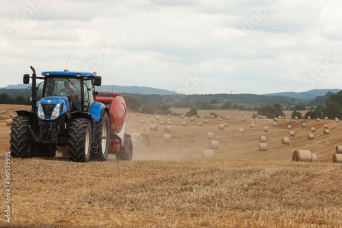 traktor making hay bales in a field - hay bale making machine