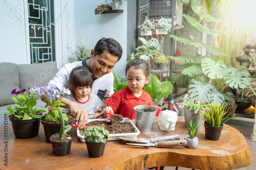 father and two daughters are happy when using a shovel to grow potted plants to fill activities at home