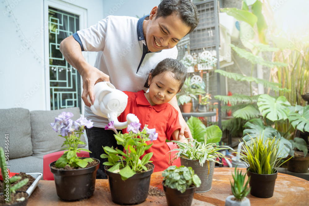 father and daughter smiled happily while holding a watering can to water the potted plants father and daughter smiled happily while holding a watering can to water the potted plants