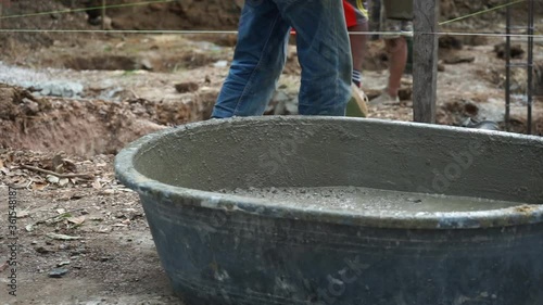 Workers delivers the bucket of mixed cement to the colleagues at the construction site
