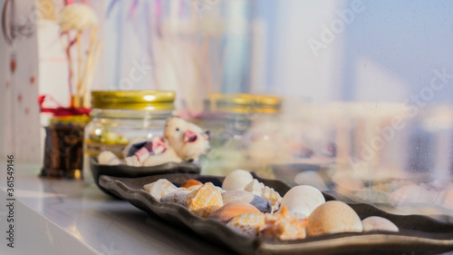Set of decorations consisting of seashells standing on the window sill with a blurred background