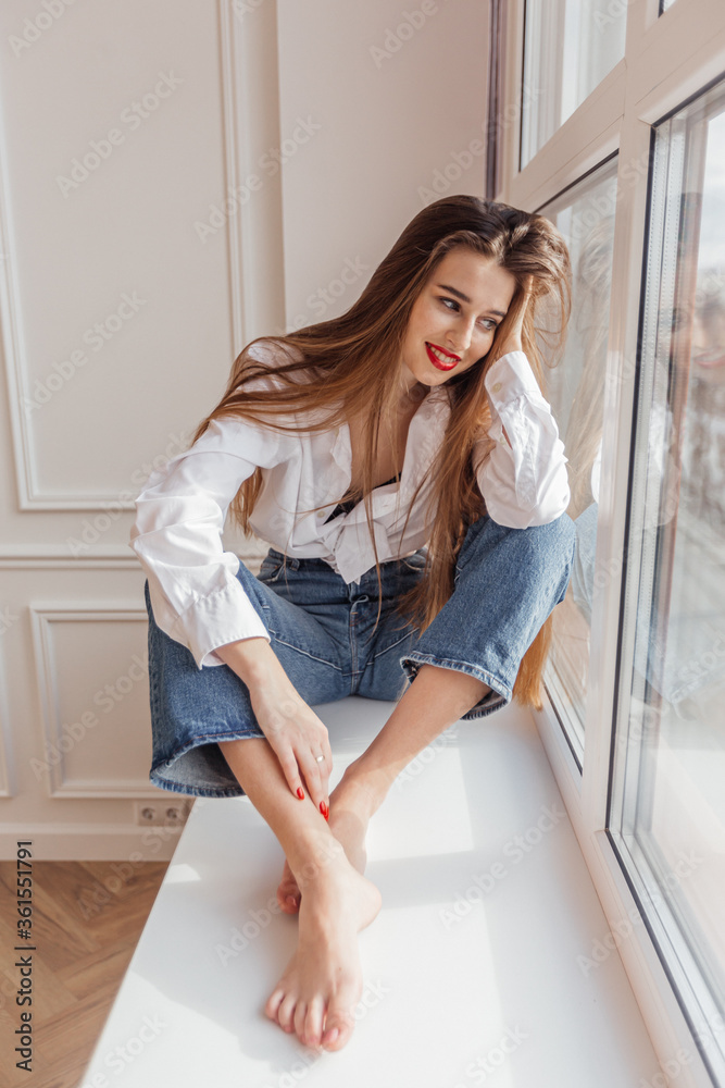 beautiful girl sitting on the window and smiling beautiful girl sitting on the window and smiling