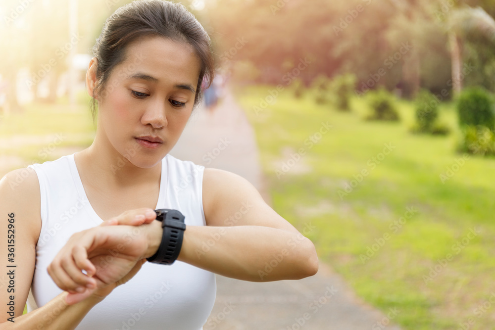 Asian Woman setting up the fitness smart watch for running. young women checking watch device. Women set smart watch before running at park. With copy space. Asian Woman setting up the fitness smart watch for running. young women checking watch device. Women set smart watch before running at park. With copy space.