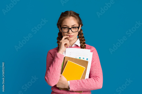 Thoughtful teenager girl with glasses and clipboards.