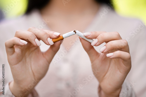 Stop smoking concept. Teenage guy breaking cigarette on turquoise background, selective focus