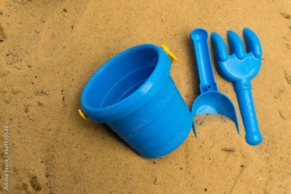 Children's games during quarantine in the sandbox. A medical mask, a shovel, a rake and a bucket for games on the street to lock down. Children's games during quarantine in the sandbox. A medical mask, a shovel, a rake and a bucket for games on the street to lock down.