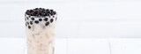Bubble milk tea with tapioca pearl topping, famous Taiwanese drink on white wooden table background in drinking glass, close up, copy space
