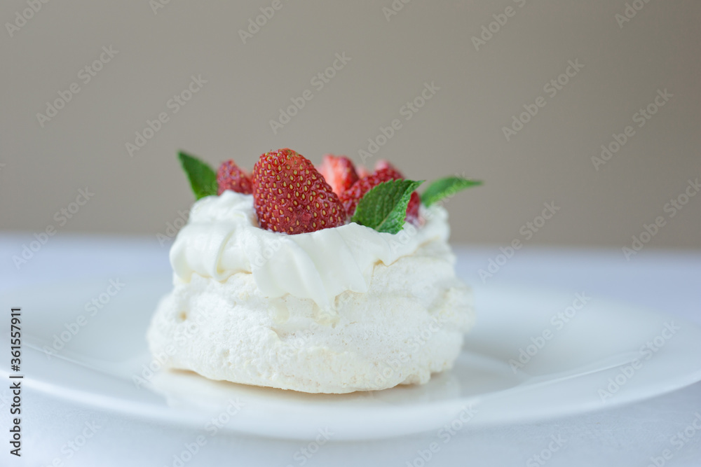 Pavlova meringue cake with whipped cream, fresh strawberry and mint on the top. Summer dessert. Selective focus. Pavlova meringue cake with whipped cream, fresh strawberry and mint on the top. Summer dessert. Selective focus.