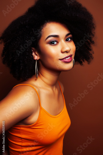 Fototapeta Naklejka Na Ścianę i Meble -  pretty young african american woman with curly hair posing cheerful gesturing on brown background, lifestyle people concept