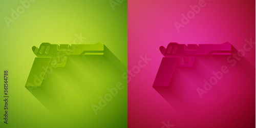 Paper cut Pistol or gun icon isolated on green and pink background. Police or military handgun. Small firearm. Paper art style. Vector Illustration.