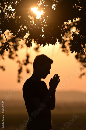 Portrait young man praying hands clasped