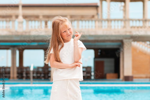 Emotions. Portrait of a little girl is standing by the pool, her legs wide apart, thinking