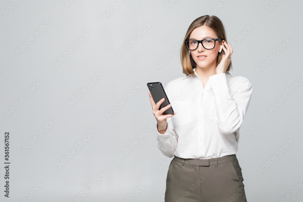 Young beautiful business woman talking via airpods wirrless headset holding phone isolated on white background Young beautiful business woman talking via airpods wirrless headset holding phone isolated on white background
