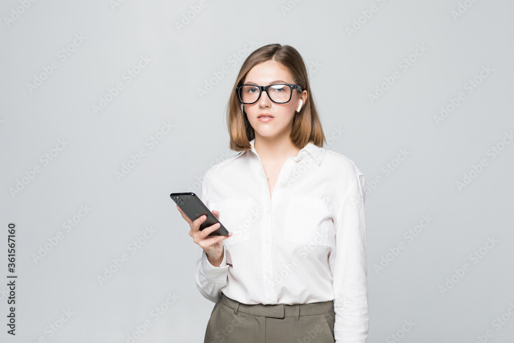 Young beautiful business woman talking via airpods wirrless headset holding phone isolated on white background Young beautiful business woman talking via airpods wirrless headset holding phone isolated on white background