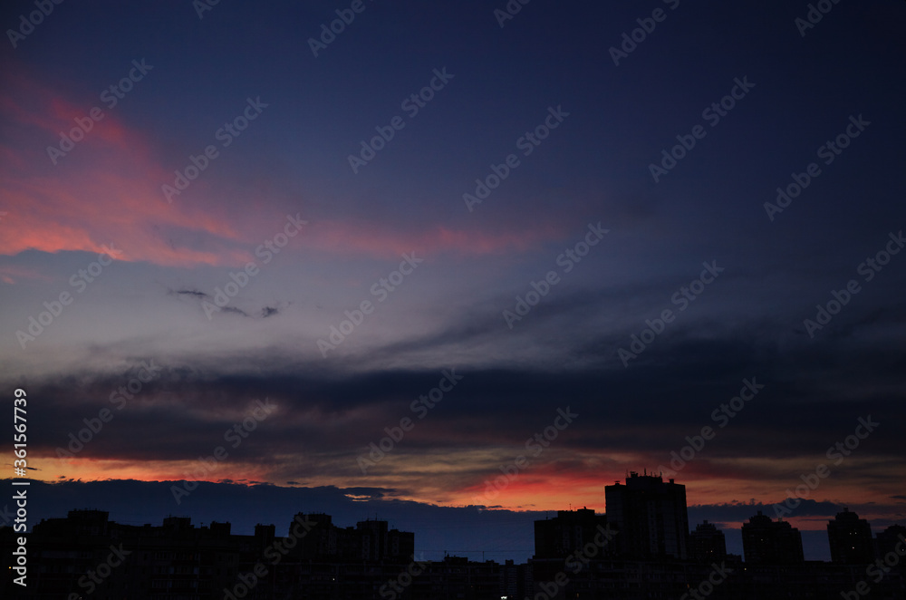 Colorful dramatic sky with cloud at sunset. City during warm sunset