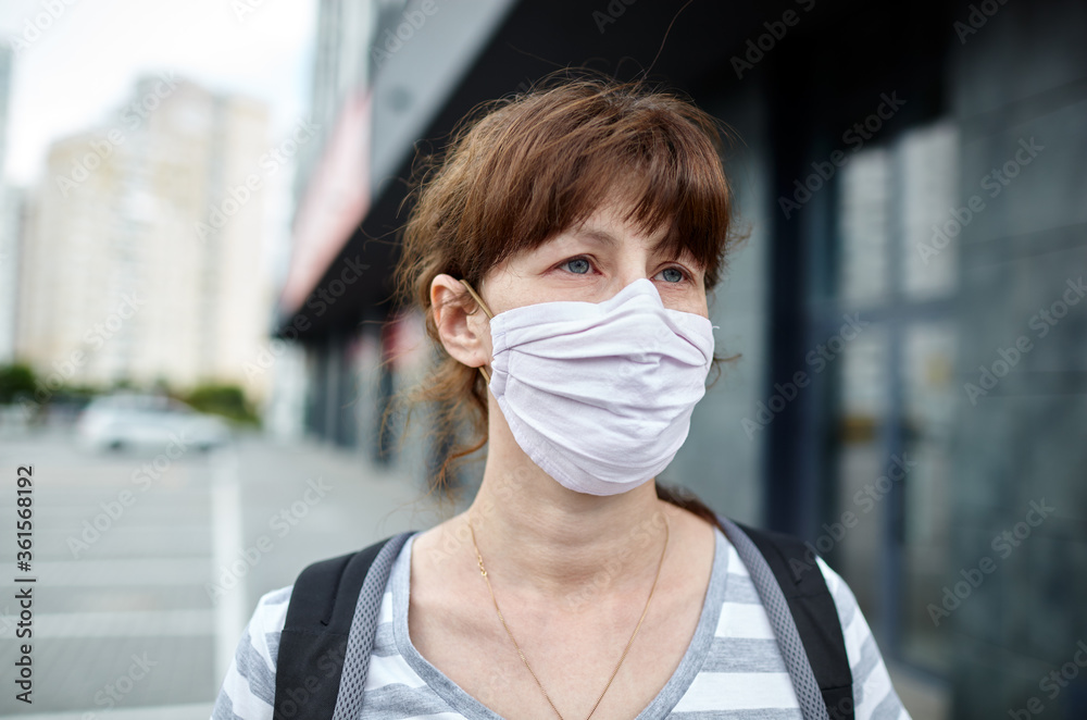 Woman wearing hygienic mask to prevent the Coronavirus. People in masks The outbreak of Novel Corona virus (2019-nCoV) in Europe. Concept of coronavirus quarantine. Air pollution