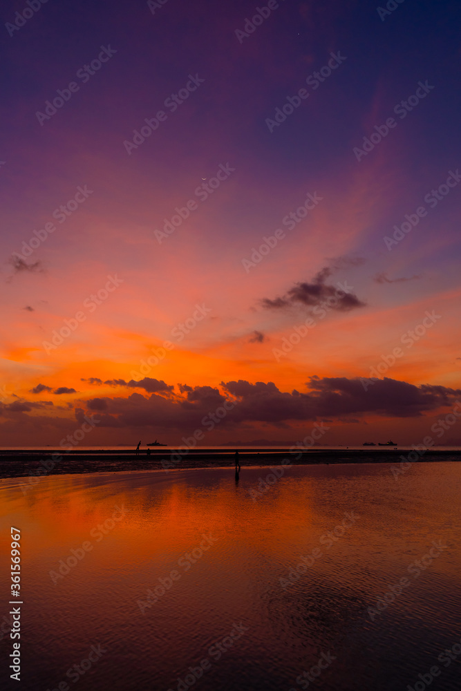 Burning bright sky during sunset on a tropical beach. Sunset during the exodus, the strength of people walking on water