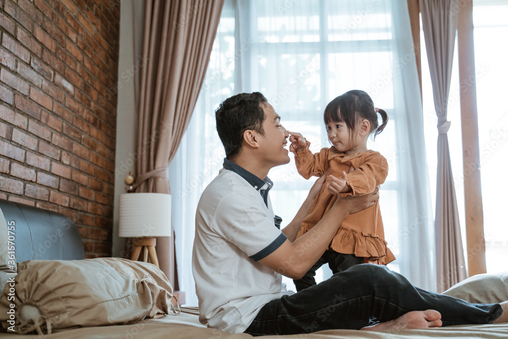 father laughed happily when his nose was touched by the little girl while playing together father laughed happily when his nose was touched by the little girl while playing together