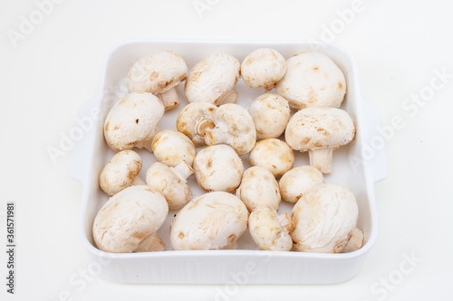 Fresh champignons in a white ceramic baking dish