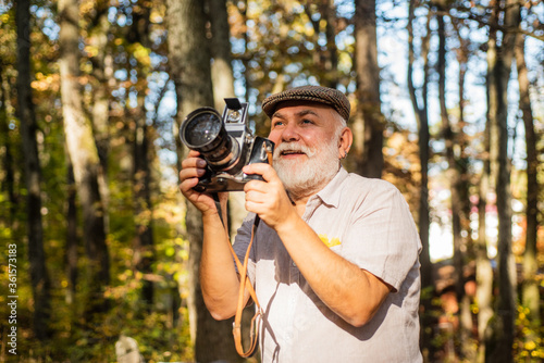 Professional photographer. Landscape and nature photo. Old photographer filming. Pension hobby. Experienced and qualified photographer. Manual settings. Old man shoot in nature. Cameraman outdoors