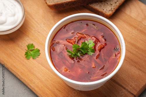 Borscht decorated with greens in a disposable dish next to sour cream and bread top view © Роман Самсонов