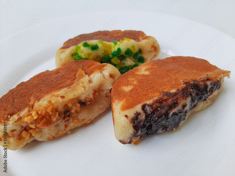 Pukis, is an Indonesian traditional pancake, with various toppings. On white plate. Isolated in white background. Pukis, is an Indonesian traditional pancake, with various toppings. On white plate. Isolated in white background.
