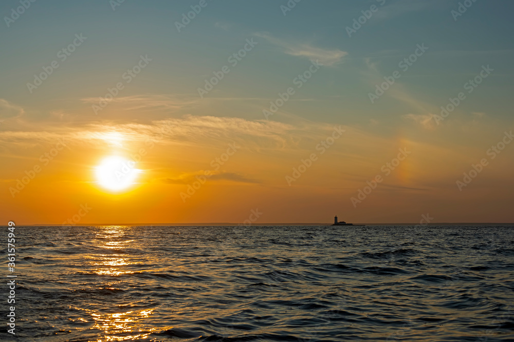 Sunset over the waters of the Bay with a sun halo and the silhouette of the lighthouse