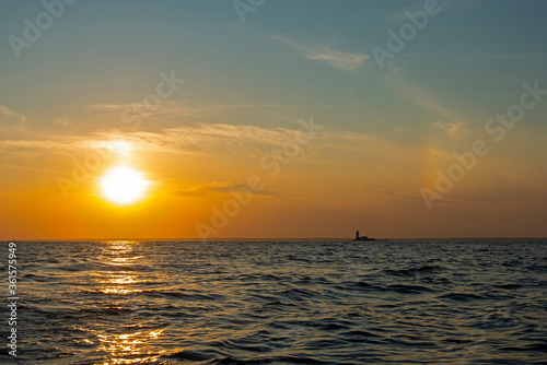 Sunset over the waters of the Bay with a sun halo and the silhouette of the lighthouse