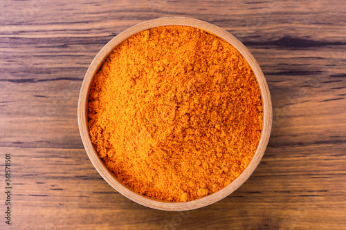 Turmeric (  curcumin, Curcuma) powder in wooden bowl isolated on wood table background. Top view. Flat lay.