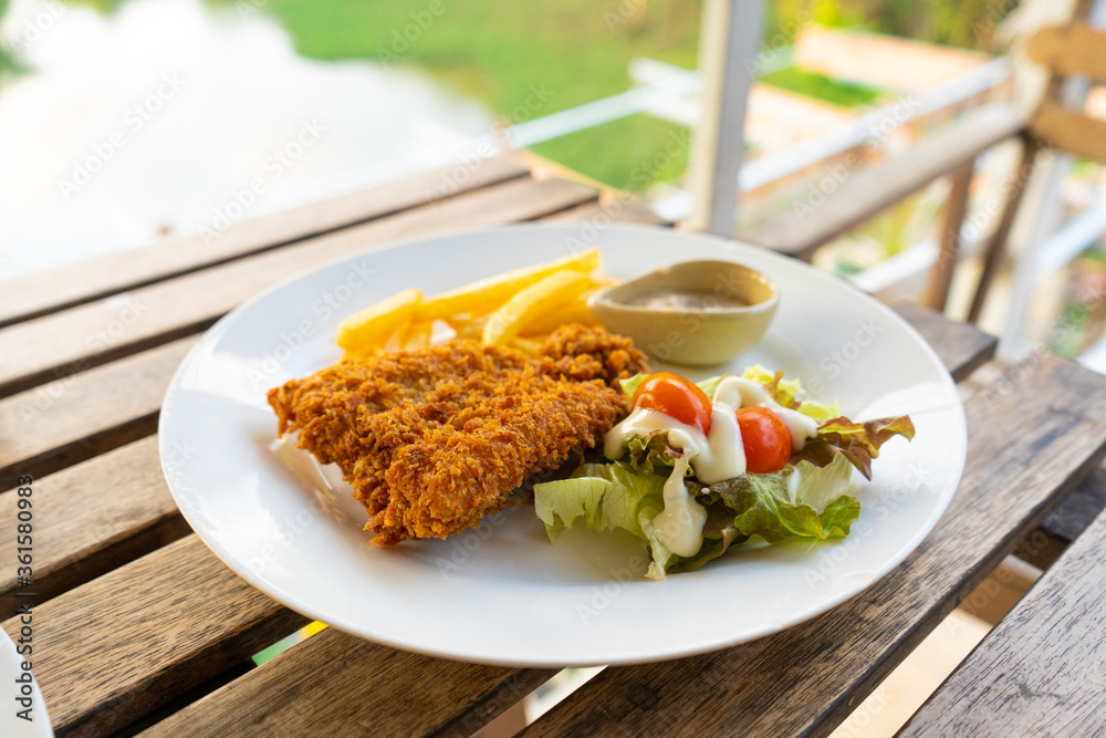 Dish Fish in batter with french fries. Fish on a plate with potatoes and salad in a summer cafe. Dish Fish in batter with french fries. Fish on a plate with potatoes and salad in a summer cafe.