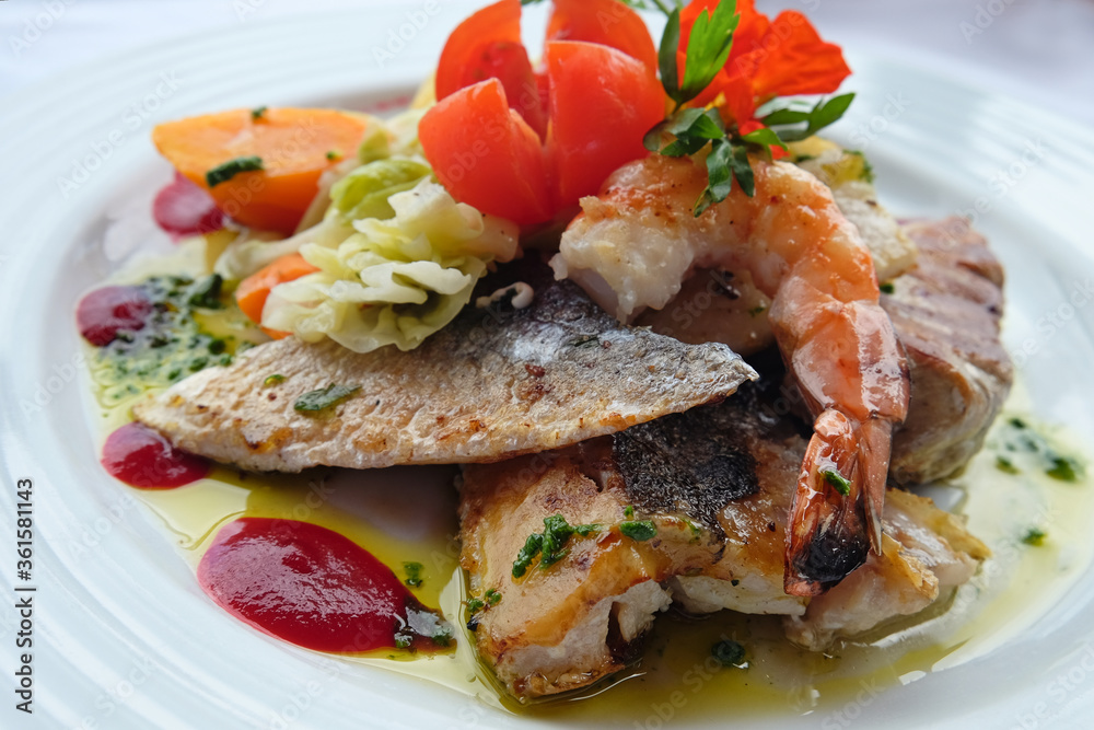 Delicious fish dish from traditional cuisine of Madeira island - grilled fillets of ocean codfish served with shrimps, shells, mussels and celery puree