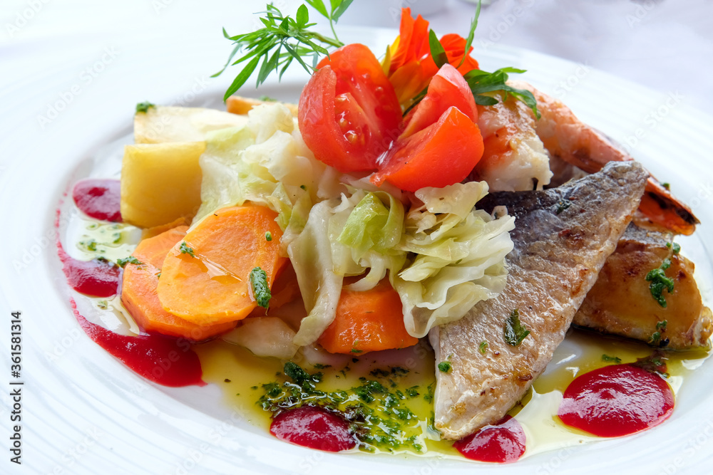 Delicious fish dish from traditional cuisine of Madeira island - grilled fillets of ocean codfish served with shrimps, shells, mussels and celery puree