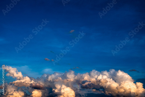Background of clear blue sky on the upper part and dramatic cumulonimbus clouds on the lower part with rays of light. Clouds over the sky.