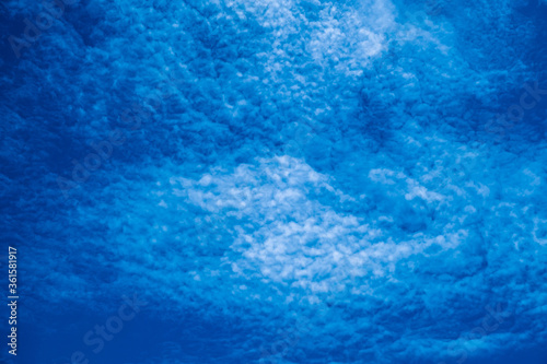 Background of lovely blue sky with altocumulus clouds scattered all over. Abstract blue background.