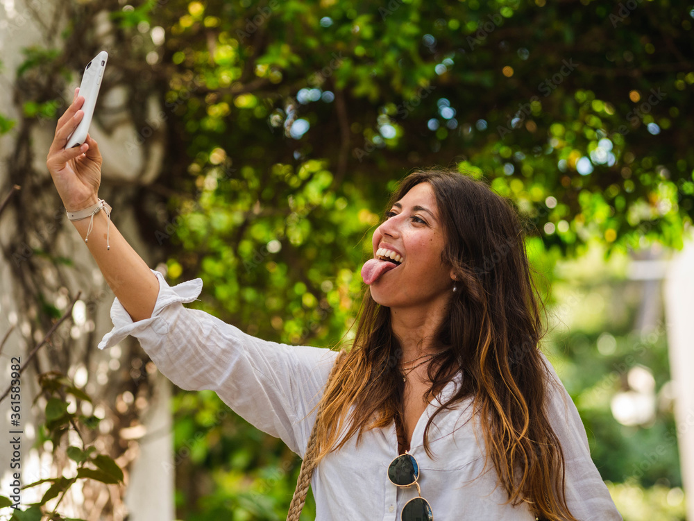 A young caucasian female smiling and using her phone while walking in the street A young caucasian female smiling and using her phone while walking in the street