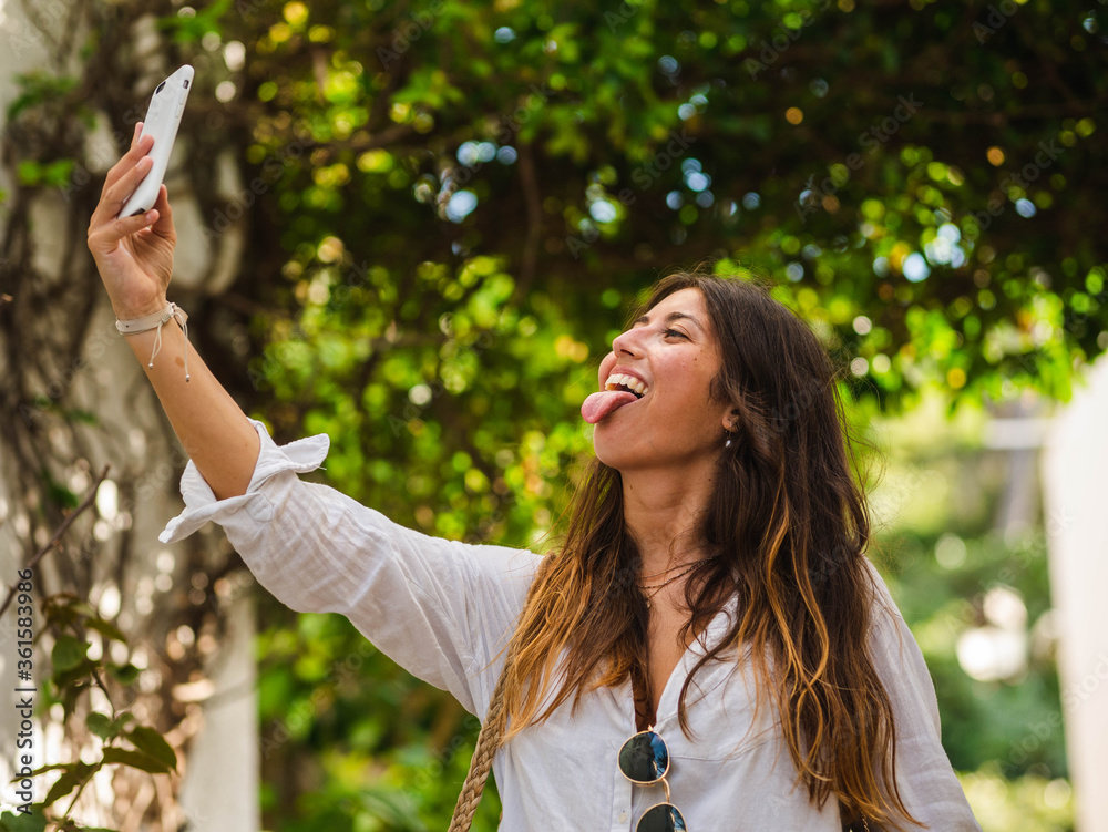A young caucasian female smiling and using her phone while walking in the street A young caucasian female smiling and using her phone while walking in the street