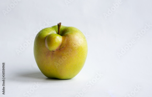 Ugly apple on a white background. Funny, unnormal fruit or food waste concept. Image with copy space, horizontal orientation.