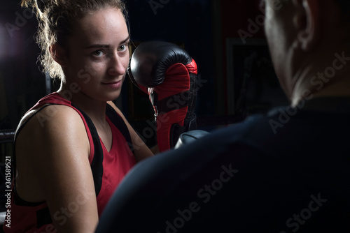 Portrait of a boxing trainer guy training a young athlete training her in martial arts. In a boxing club. Girls learn self-defense, martial art.