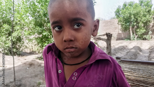 closeup of a poor staring hungry orphan boy in a refugee camp with sad expression on his face and his face and clothes are dirty and his eyes are full of pain