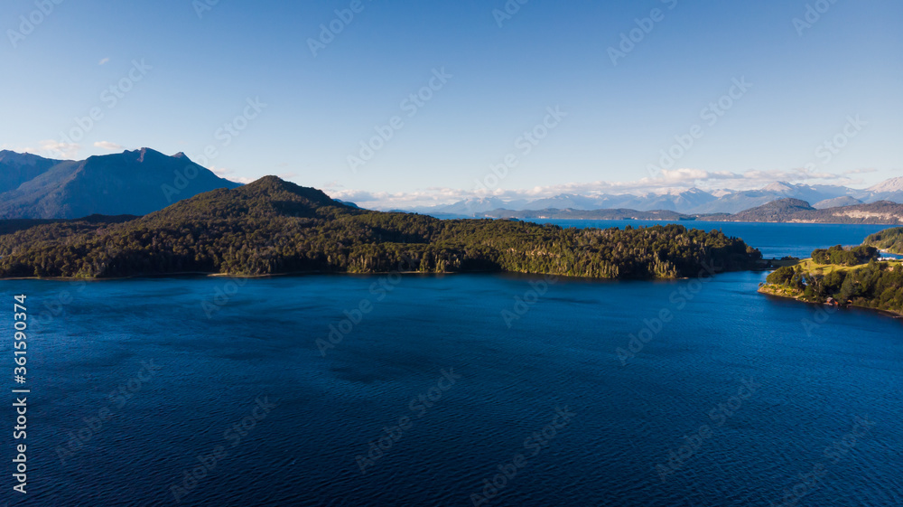 Aerial view of a forest lake. Aerial view of the blue lake and green forests on a sunny summer day. Top view of Patagonia.