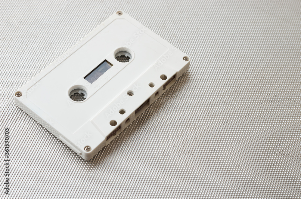 White audio cassette without markings isolated on metal backdrop. Close-up shot White audio cassette without markings isolated on metal backdrop. Close-up shot
