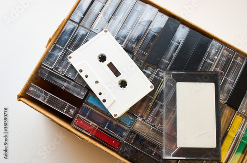 Single white audio cassette without markings on top of the box with many tapes. Close-up shot