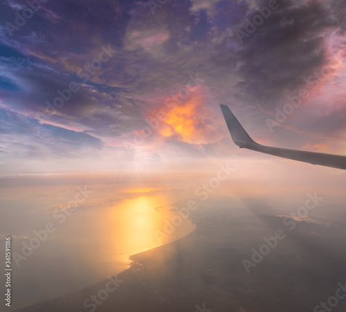 Wing of the air plane on the sea of cloud sunset sky background from window airplane © lukyeee_nuttawut