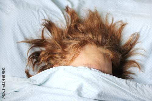 A woman with a messy hair sleeping in the bed, close up