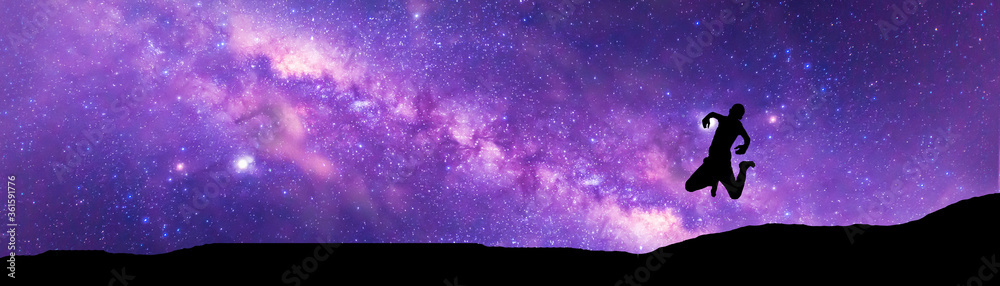 Obraz premium Amazing Panorama blue night sky milky way .Universe filled with stars, nebula and galaxy with noise and grain.Photo by long exposure and select white balance.Dark night sky.Silhouette of man jumping .